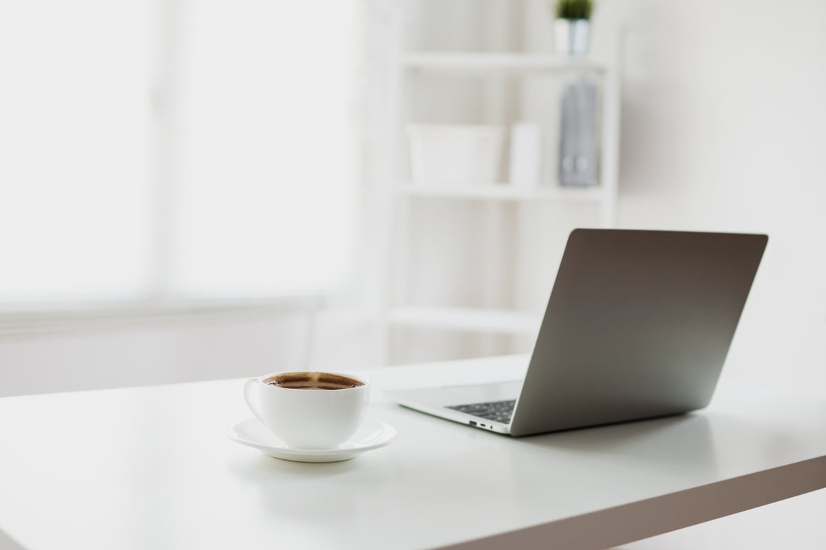 white and clear office room with laptop and coffee on table